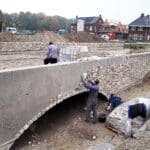 Natuurstenen plaatsen op brug.